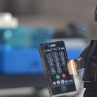 Lego minifigure holding a Lego mobile phone and standing in front of a blue Lego utility truck