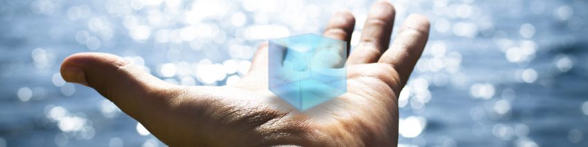 Against the backdrop of a sparkling lake, an outstretched palm holds a blue, virtual cube.