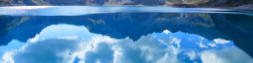 Mountains and a bright, cloudy sky reflected in a clear lake