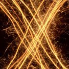 Over a black background, golden light streaks in the pattern of an "X" inscribed in a circle