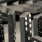 Black dominos with white dots in a curved row. Half fallen. Half upright.