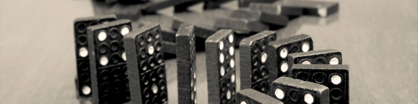 Black dominos with white dots in a curved row. Half fallen. Half upright.